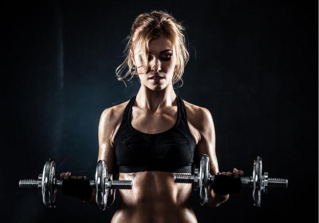 Woman lifting weights in gym, focused and determined.